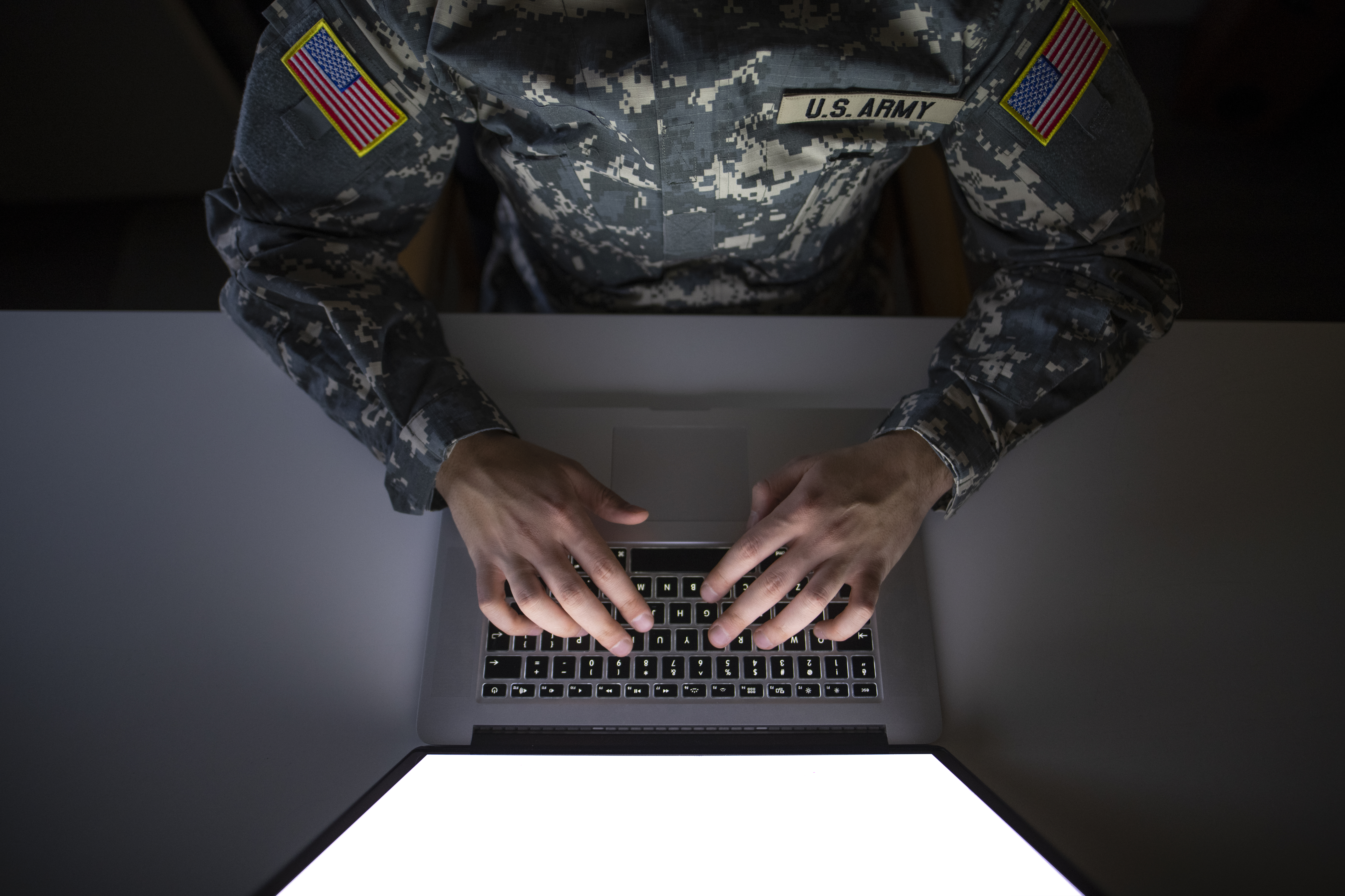 U.S. Army service member using secure laptop to support defense IT and mission systems.